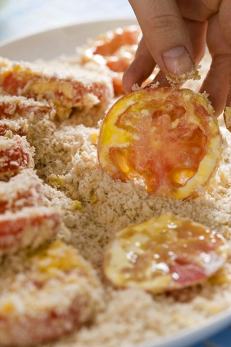 Tomato slices being dusted in breadcrumbs