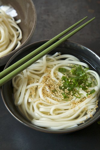 Bowl of Udon Soup with Green Onion and Sesame Seeds; Chopsticks