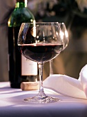 Ein Glas Rotwein auf weißem Tischtuch