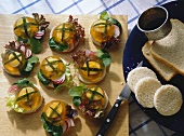 Small Aspic with Quail Eggs on round toasted Bread Slices with Lettuce and Radishes wooden Board