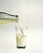 Milch aus einer Milchflasche in ein Glas gießen