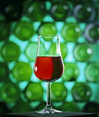 Rotweinglas vor dem Hintergrund zahlreicher Flaschenböden