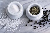 Salt and pepper in containers, peppercorns and sea salt