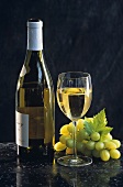 Weißweinstilleben mit Burgunderflasche, Glas und Weintraube
