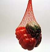 Rote und grüne Paprikaschoten hängen im Netz