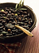 Clay bowl with black olives; wooden spoon