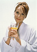 Young woman in bathrobe with a glass of orange juice