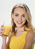 Junge blonde Frau mit einem Glas Orangensaft