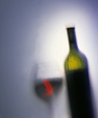 Silhouette of a red wine glass next to a red wine bottle; blue