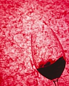 Swirling red wine glass against red background