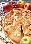 Wholemeal apple pie on wooden plate with apples