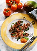 Three grilled veal kebabs with bacon on plate