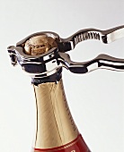 Opening a sparkling wine bottle with champagne tongs