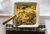Sauerkraut with juniper berries in china bowl with spoon