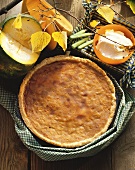 A pumpkin pie on wooden table with bowl of cream