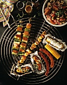 Grilled corn cobs, sausages & kebabs on grill; bean salad