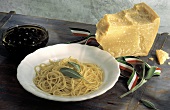 Butterspaghetti mit Salbei auf Teller neben Parmesan & Oliven