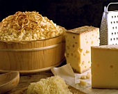 Käsespätzle in Holzschüssel, daneben Käse & geriebener Käse