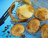 Kartoffeln auf Netz, eine halb geschält mit Sparschäler
