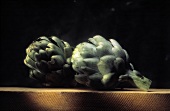 Two Whole Artichokes on a Wood Board