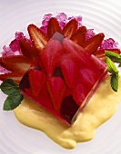 A cube of strawberry jelly with mint leaves on vanilla sauce