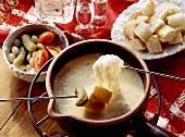 Skewers with bread & mixed pickles above cheese fondue