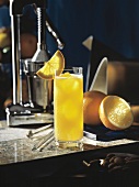 Ein Glas Orangensaft auf Tisch, Deko: Saftpresse, Orangen