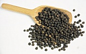 Black Peppercorns Spilling out of a Wooden Scoop