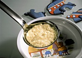 Porridge on ladle above child's plate