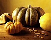 Three different pumpkins & pumpkin seeds on wooden table