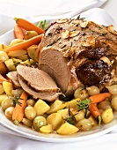 Leg of lamb with roast garlic slices on vegetables