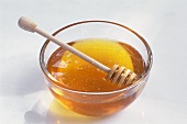 Flüssiger Honig im Glasschälchen mit Honiglöffel