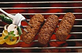 Three mince rolls on the grill and vegetable slices