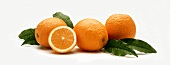 Drei ganze Orangen sowie eine Hälfte & Blätter