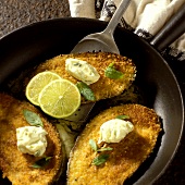 Breaded aubergine slices with herb butter in pan