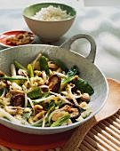 Vegetables, sprouts & mushrooms in wok, décor: bowl of rice