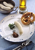 A white sausage (Weisswurst) with mustard on a plate
