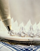 Piping meringue rosettes on meringue base with icing pipe