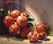 Whole Pomegranates in a Wire Basket; One Cut in Half