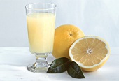 A glass of grapefruit juice, with whole & half grapefruit