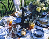Gedeckter Tisch mit blau-weißem Geschirr & Eistee im Freien