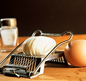 Ein gekochtes, geschältes Ei im Eierschneider, Deko: Ei, Salz
