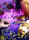 Oyster, oyster-knife, -glove & pearl on violet background
