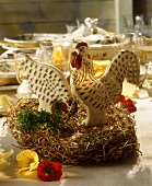 Easter table decoration: wooden cock and hen on straw nest