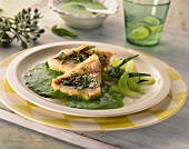 Red perch fillets with green sauce and cucumber on plate
