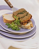 A slice of meatloaf with herb stuffing on server