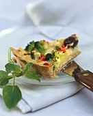 A piece of broccoli quiche with vegetables & olives