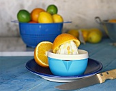 Orange on plastic lemon squeezer, citrus fruits behind
