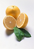 Halved yellow grapefruit with leaves by whole grapefruit