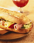 Baguettesandwich belegt mit Salat, Schinken- und Käseröllchen